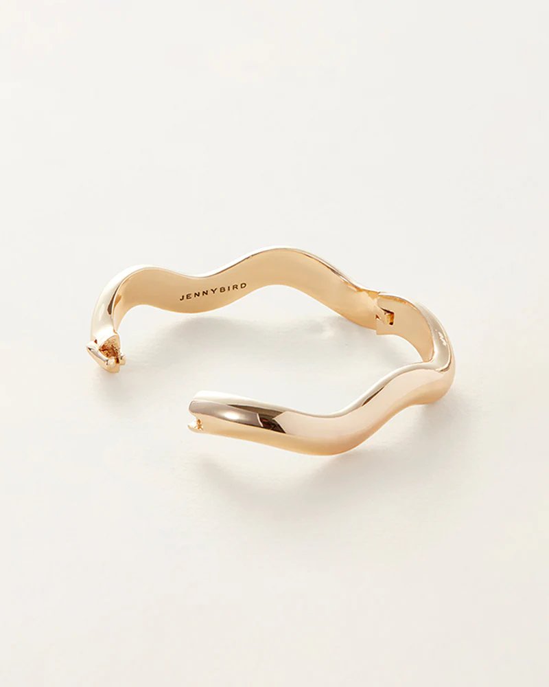 Jenny Bird Ola bangle in high polish gold. Curved gold bangle with an opened hinge and tab lock closure.