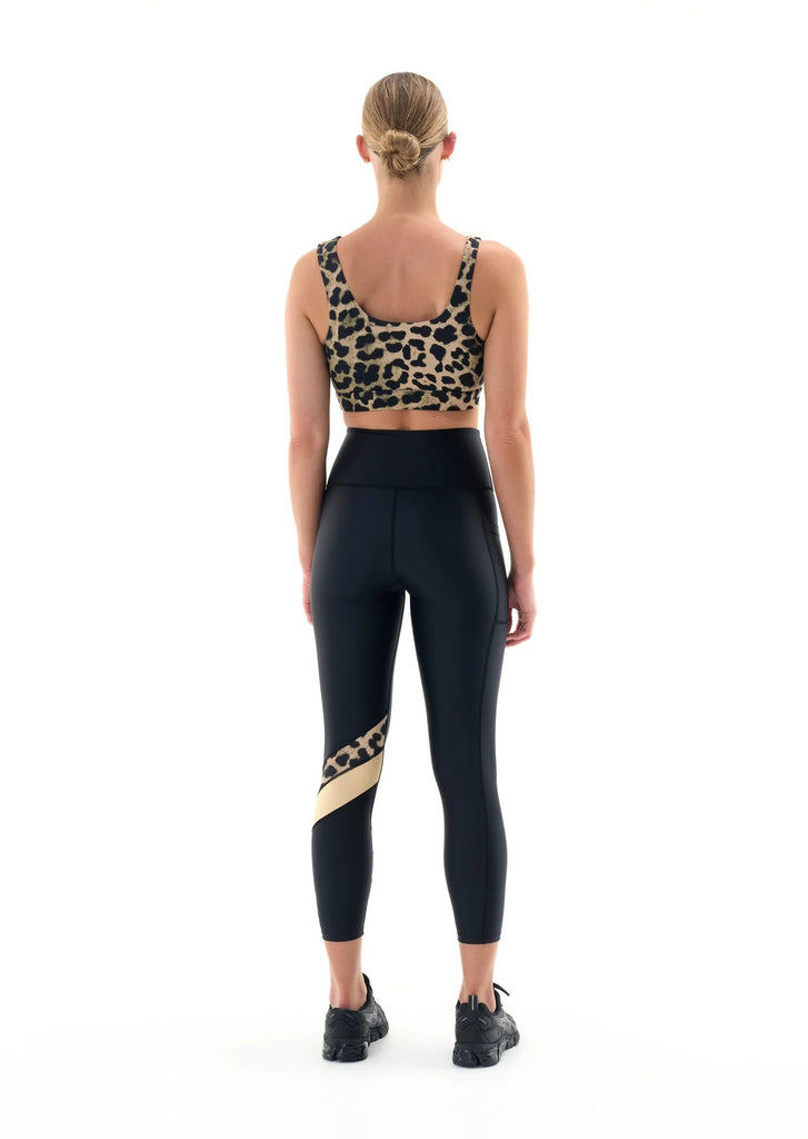 p.e. nation alignment legging in black model gold stripe colorblock behind view