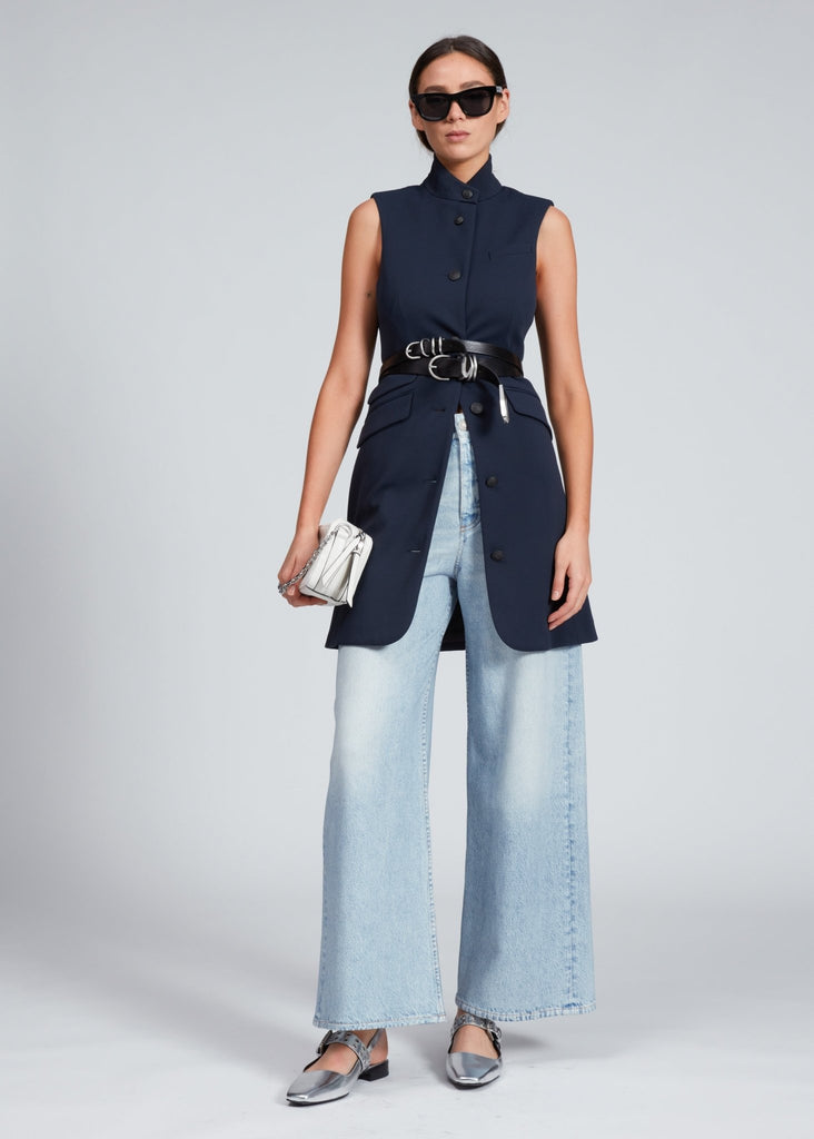 Model wearing the rag and bone women's slade knit twill vest dress in navy styled with jeans and two black belts, and silver shoes